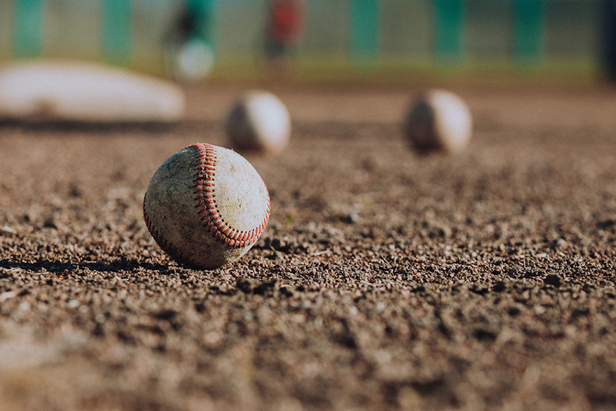 Close up of baseballs lying on dirt baseball diamond.